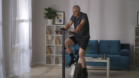 prevention-of-cardiovascular-disease-in-middle-age-man-is-training-on-stationary-bicycle-in-home-keeping-good-physical-condition